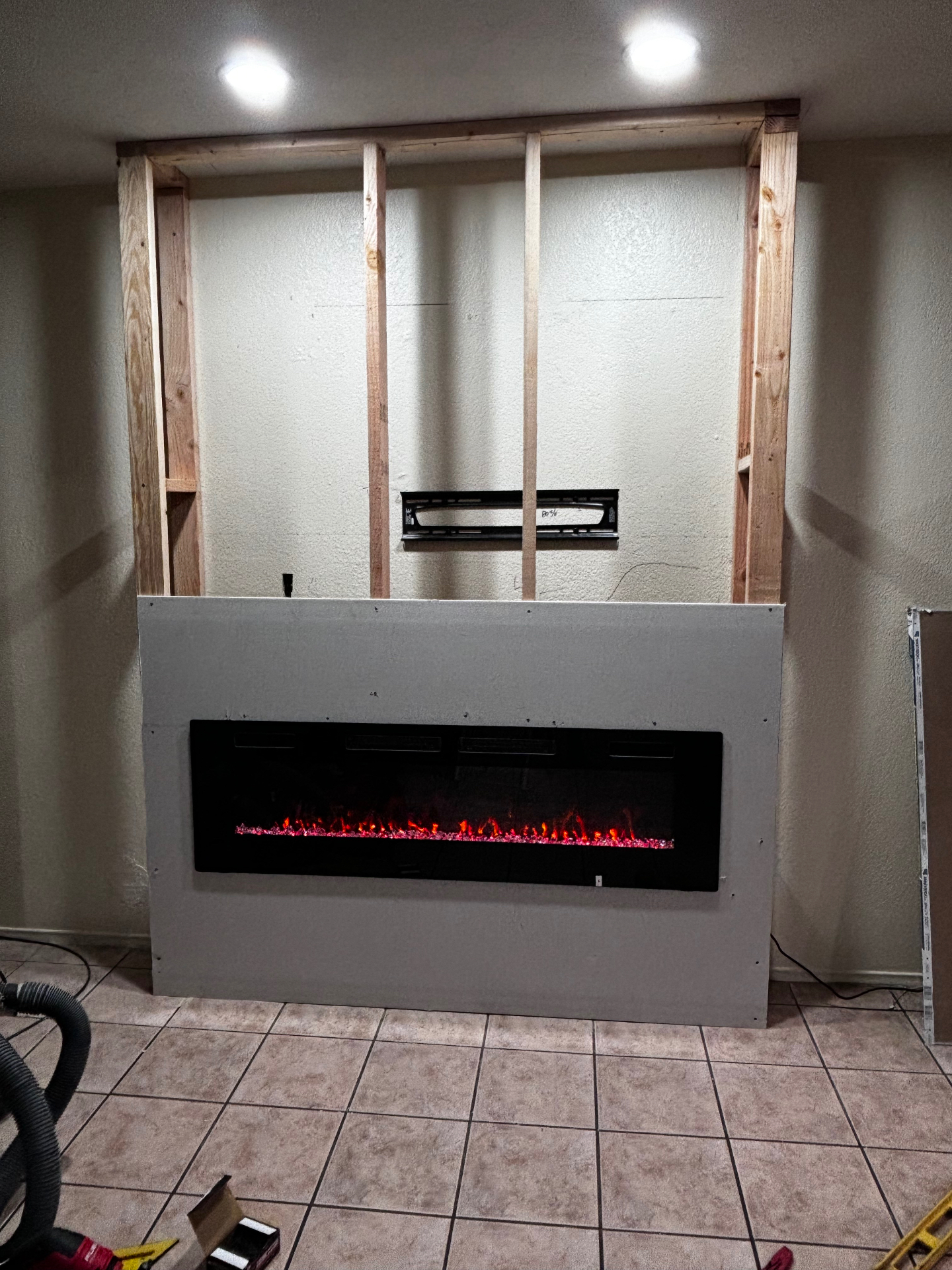 Electric fireplace insert set into new framed wall