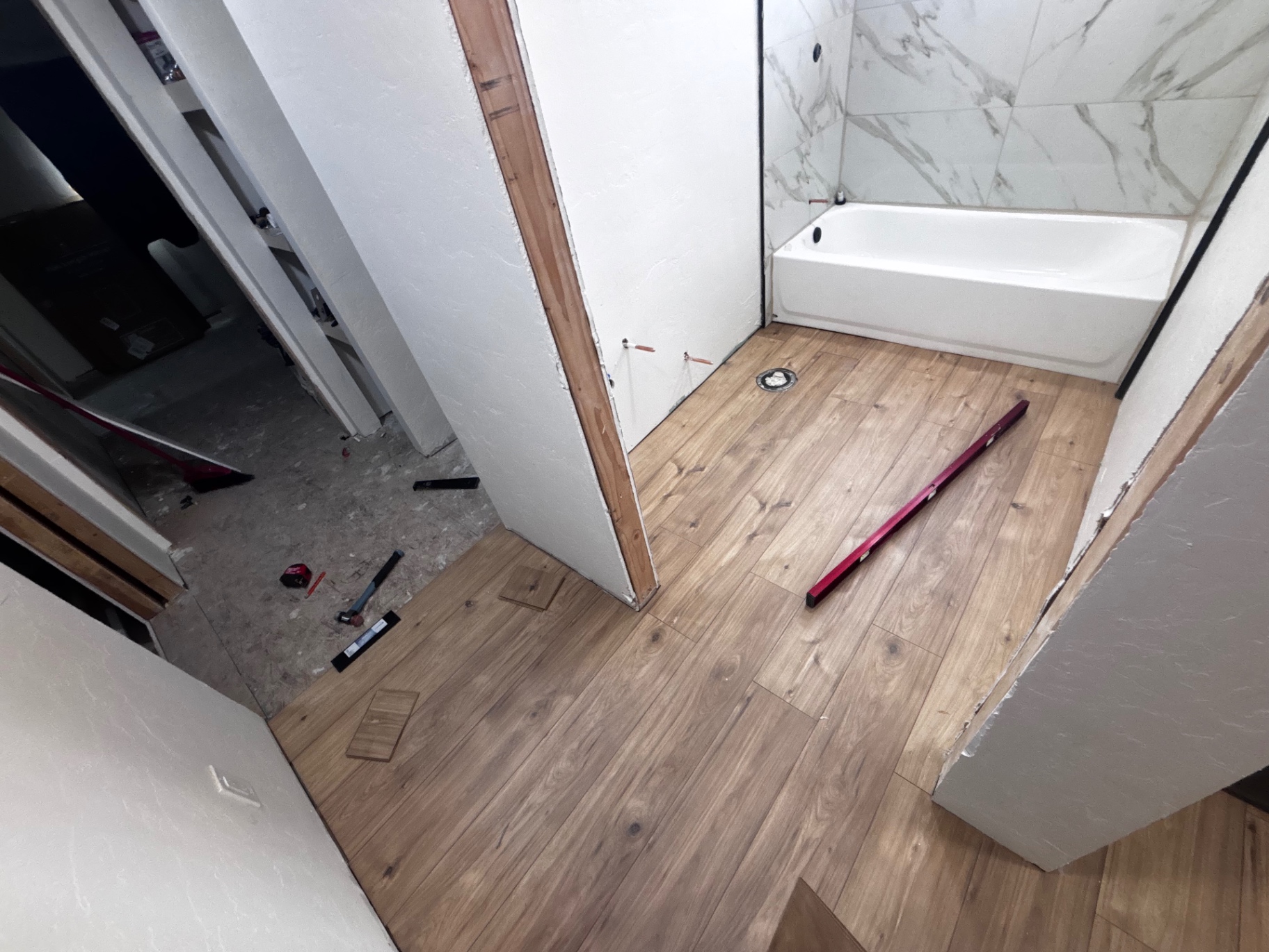Bathroom mid-renovation with new flooring and tub surround