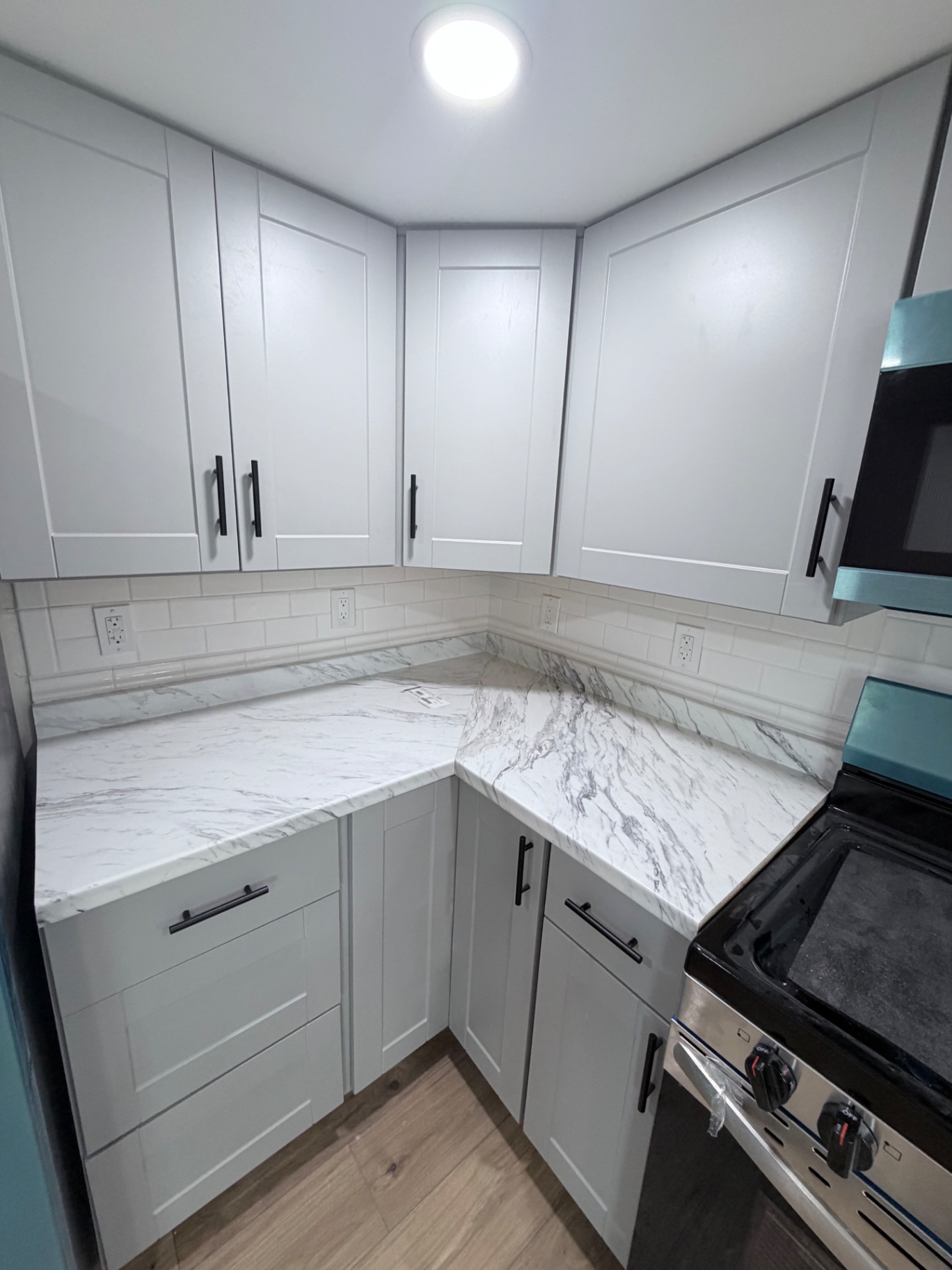 Finished kitchen corner with subway tile and marble counters